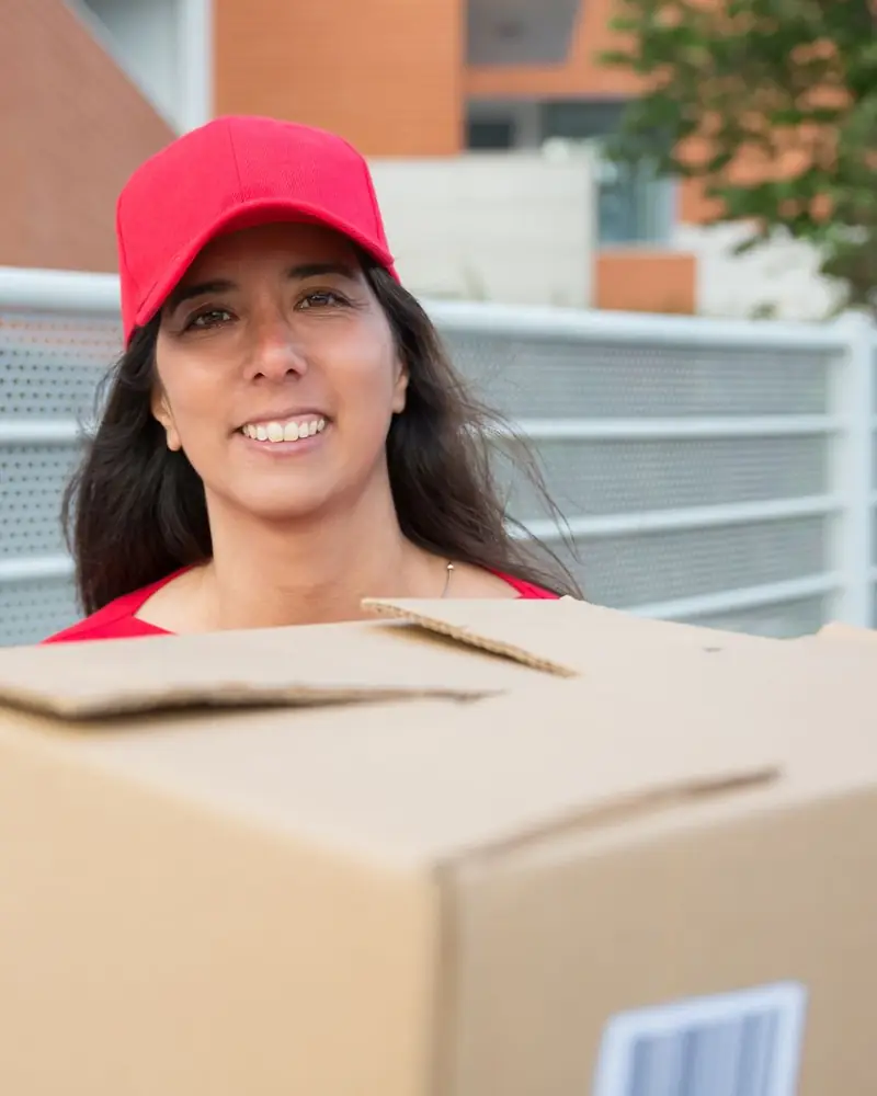 Auxiliar de empaque cargando una caja